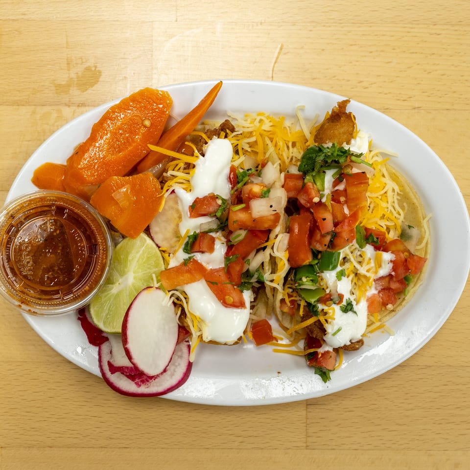 Loaded Mexican-style platter topped with shredded cheese, pico de gallo, sour cream, carrots, radishes, lime, and dipping sauce.